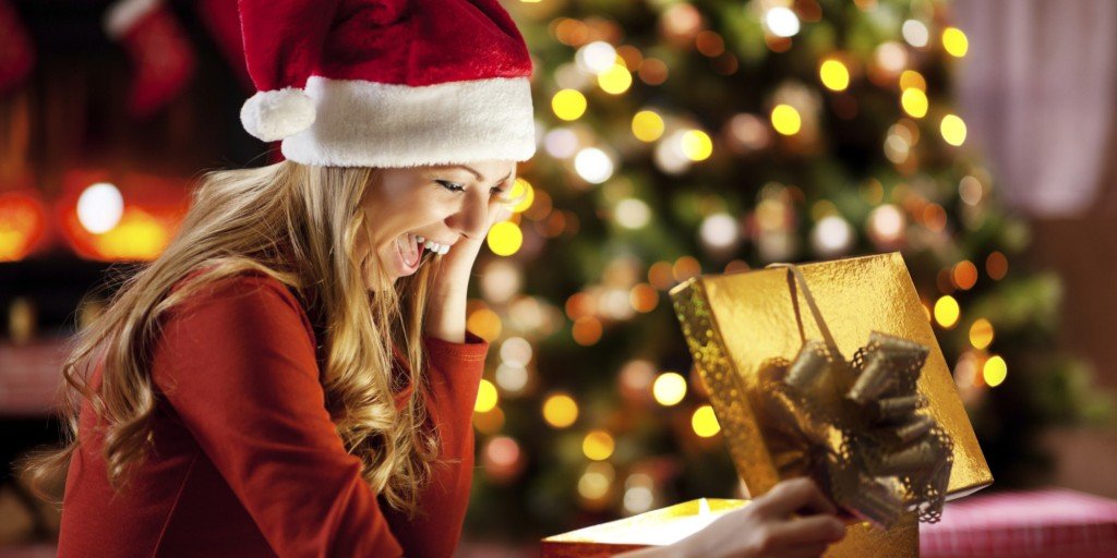 Ecstatic woman opening Christmas presents.